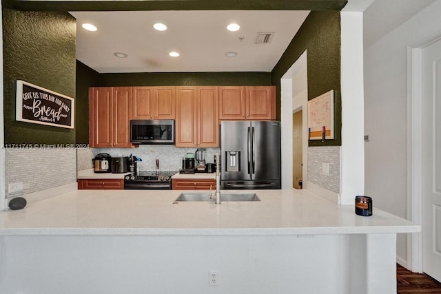 kitchen featuring sink, dark hardwood / wood-style floors, tasteful backsplash, kitchen peninsula, and stainless steel appliances