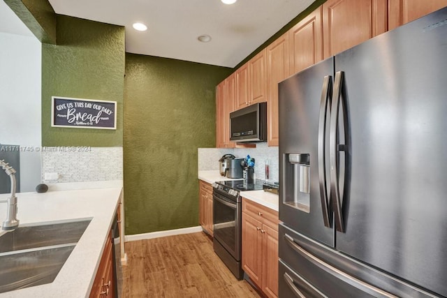 kitchen with black appliances, backsplash, light wood-type flooring, and sink