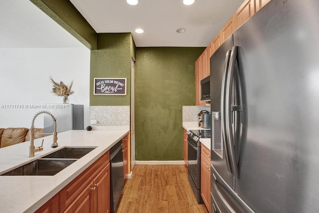 kitchen featuring backsplash, sink, black appliances, and light hardwood / wood-style floors