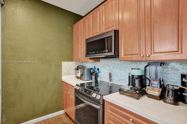 kitchen with tasteful backsplash, black range with electric stovetop, and light hardwood / wood-style flooring