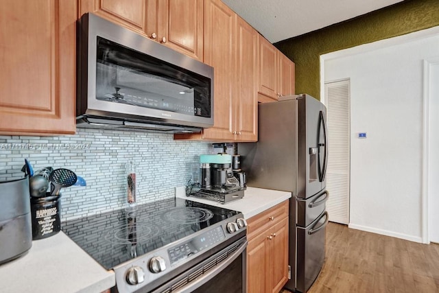 kitchen featuring appliances with stainless steel finishes, backsplash, and light hardwood / wood-style floors