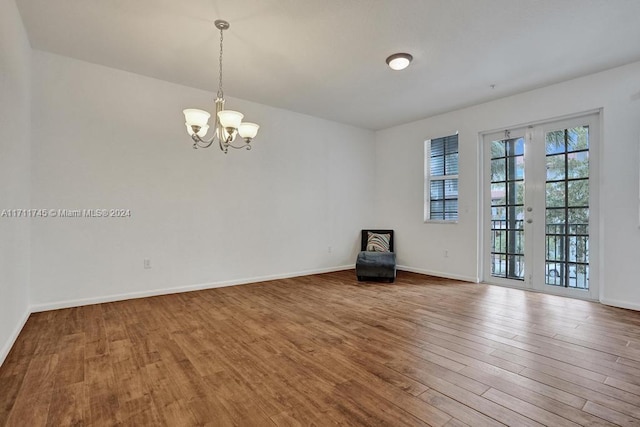 spare room with hardwood / wood-style flooring and a notable chandelier