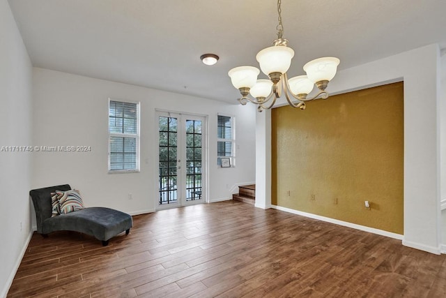 empty room with hardwood / wood-style flooring, an inviting chandelier, and french doors