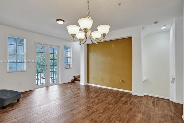 unfurnished room with a chandelier, hardwood / wood-style floors, and french doors