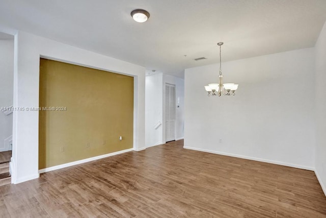 empty room featuring hardwood / wood-style flooring and an inviting chandelier