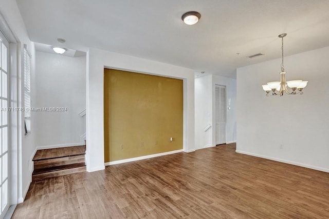 empty room featuring a chandelier and hardwood / wood-style flooring