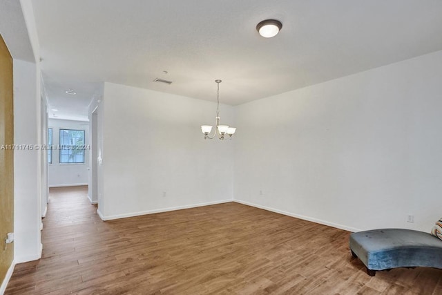 unfurnished room with a chandelier and wood-type flooring