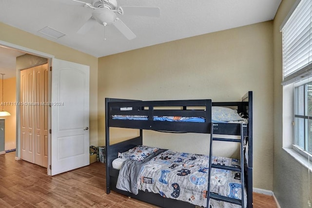 bedroom with hardwood / wood-style floors, ceiling fan, and multiple windows