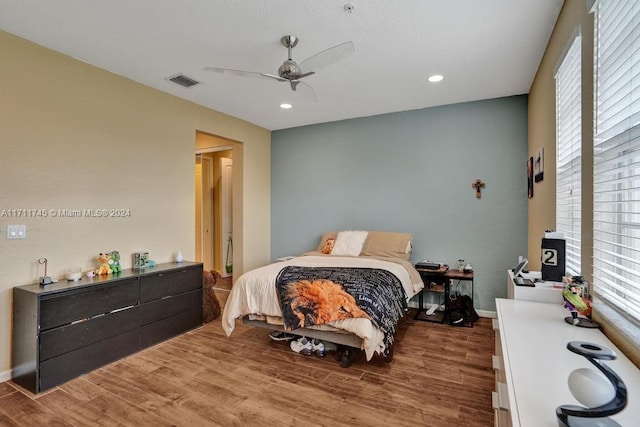 bedroom with hardwood / wood-style floors, multiple windows, and ceiling fan