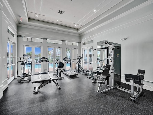 exercise room featuring french doors, a raised ceiling, crown molding, and a high ceiling