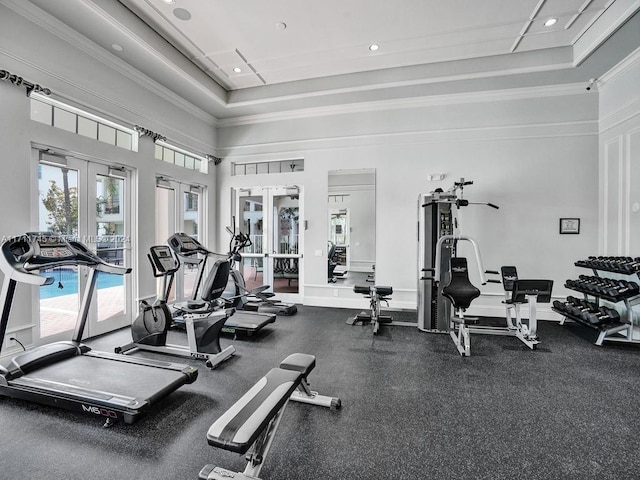 exercise room with a raised ceiling, ornamental molding, a towering ceiling, and french doors