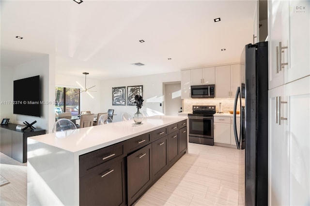 kitchen with dark brown cabinets, appliances with stainless steel finishes, a kitchen island, white cabinets, and backsplash