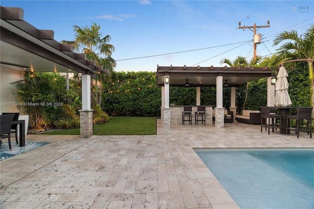 view of patio featuring a fenced in pool, ceiling fan, and a bar