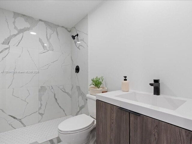 full bathroom with toilet, a marble finish shower, and vanity