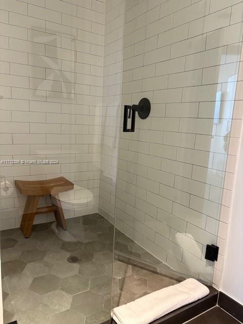 bathroom with a tile shower and toilet