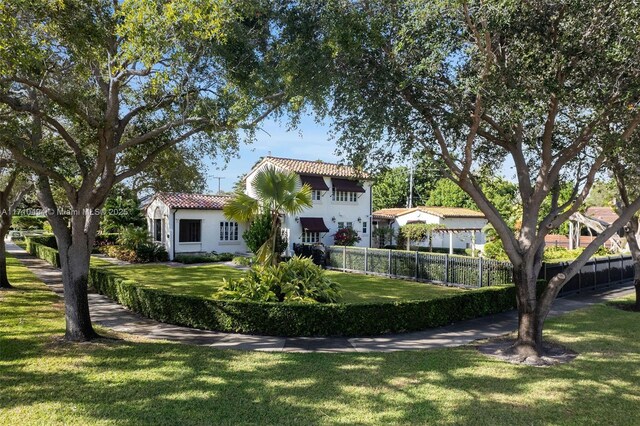 back of property with a tiled roof, a lawn, fence, and stucco siding