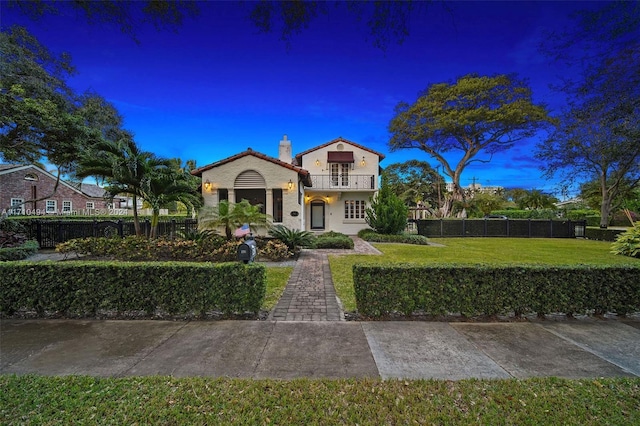 mediterranean / spanish-style house featuring a front yard and a balcony