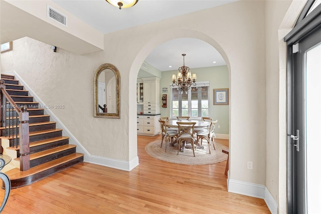 interior space featuring visible vents, baseboards, stairs, light wood-type flooring, and a notable chandelier