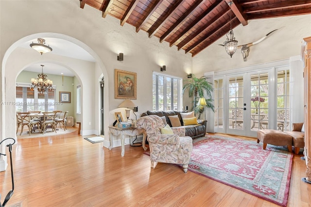 living area with wooden ceiling, light wood-style flooring, a notable chandelier, and beam ceiling