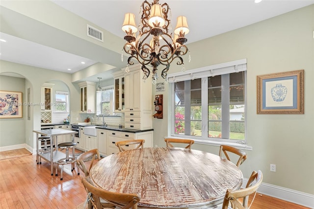 dining space with visible vents, baseboards, light wood-style floors, and arched walkways