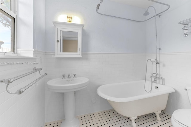 bathroom featuring a wainscoted wall, toilet, a soaking tub, tile walls, and a shower