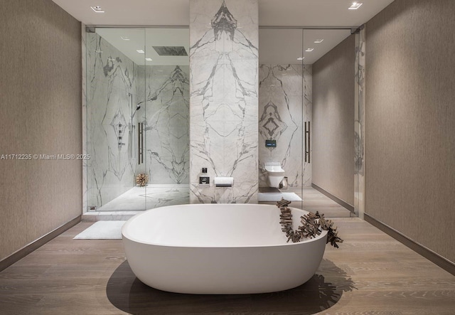 bathroom with a marble finish shower, visible vents, a soaking tub, wood finished floors, and stone wall