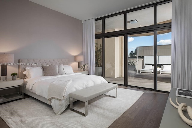 bedroom featuring access to outside, a wall of windows, and wood finished floors