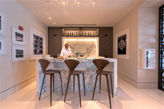 bar featuring baseboards, backsplash, and a dry bar