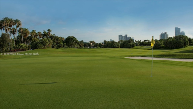 view of home's community with golf course view, a lawn, and a city view