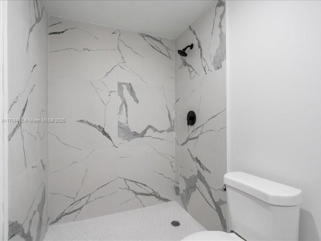 bathroom with a marble finish shower and toilet