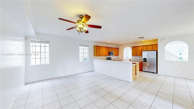 kitchen with kitchen peninsula, ceiling fan, light tile patterned flooring, and stainless steel appliances