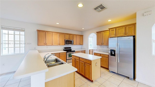 kitchen with light tile patterned floors, a center island, stainless steel appliances, and sink