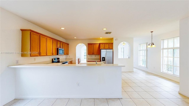 kitchen with pendant lighting, an inviting chandelier, light tile patterned floors, appliances with stainless steel finishes, and kitchen peninsula