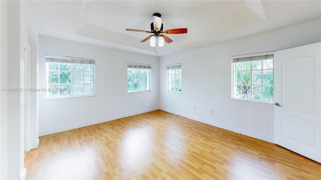 spare room with light wood-type flooring, a raised ceiling, and ceiling fan