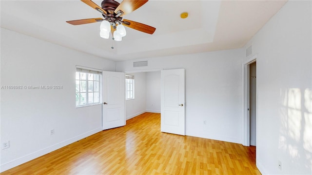 unfurnished bedroom with a raised ceiling, ceiling fan, and light hardwood / wood-style flooring