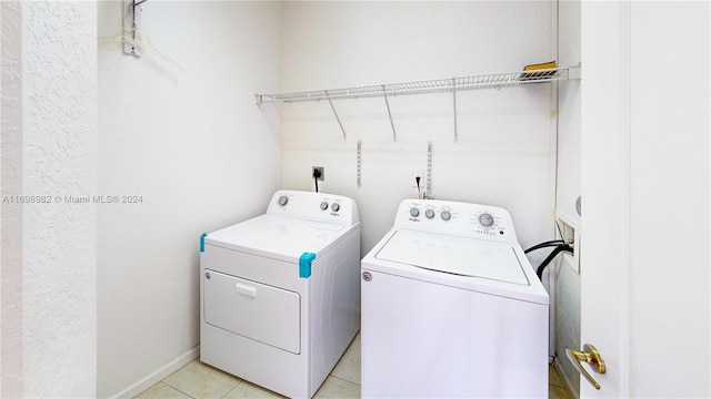 clothes washing area with light tile patterned floors and washing machine and clothes dryer