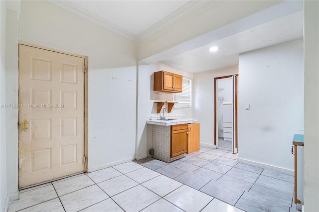 kitchen with ornamental molding, sink, and light tile patterned floors