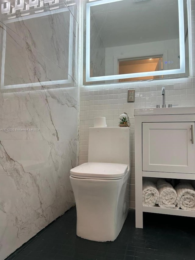 bathroom with vanity, toilet, and tile walls