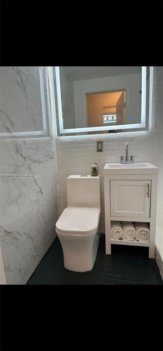 bathroom with vanity, tile walls, and toilet