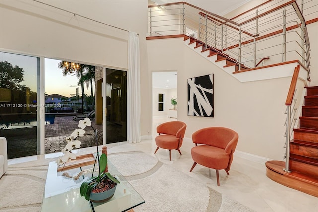 living room featuring a notable chandelier, crown molding, and a high ceiling