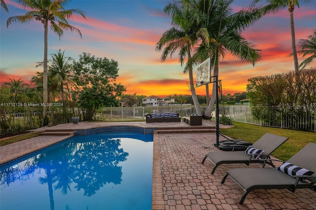 pool at dusk with an outdoor living space and a patio