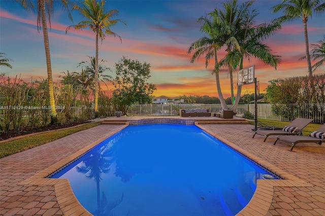 pool at dusk featuring a patio