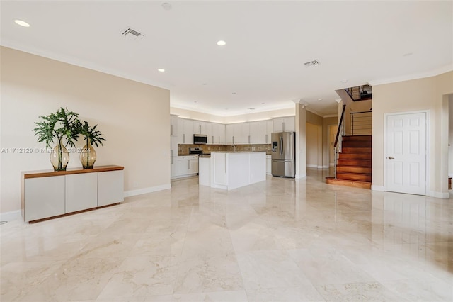 interior space featuring white cabinetry, a center island, stainless steel appliances, crown molding, and decorative backsplash