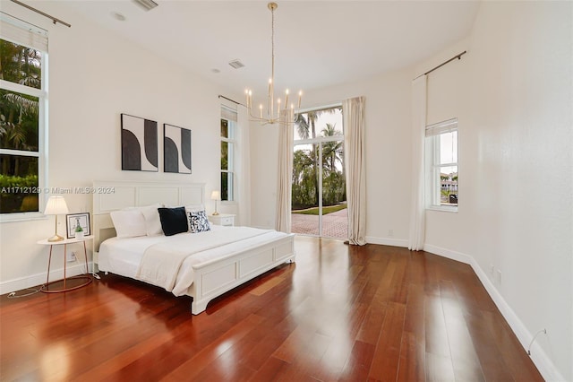 bedroom with access to outside, dark hardwood / wood-style floors, and a notable chandelier