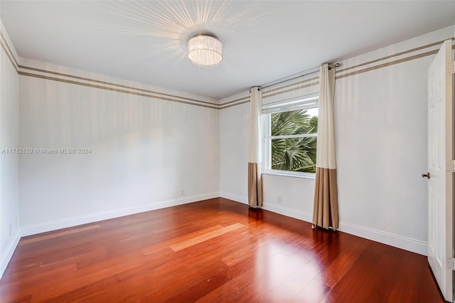 unfurnished bedroom with hardwood / wood-style flooring and a chandelier