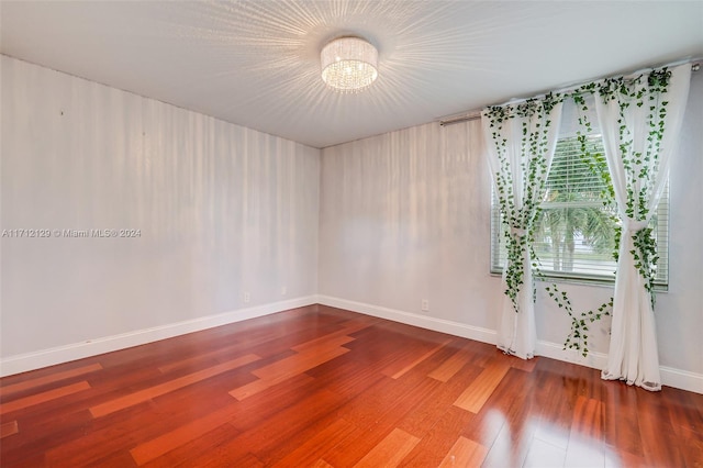 unfurnished room with hardwood / wood-style flooring and an inviting chandelier