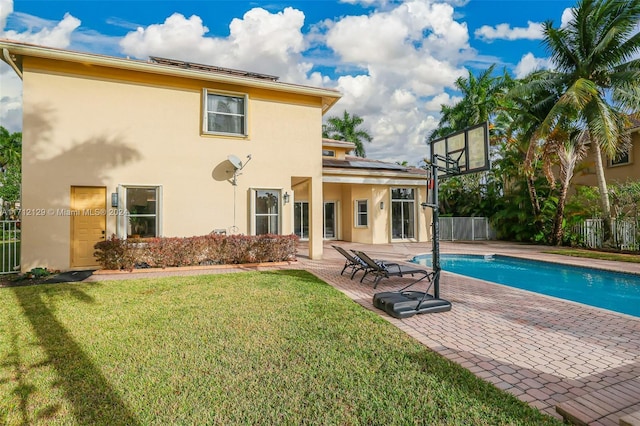 rear view of property featuring a yard, a fenced in pool, and a patio area