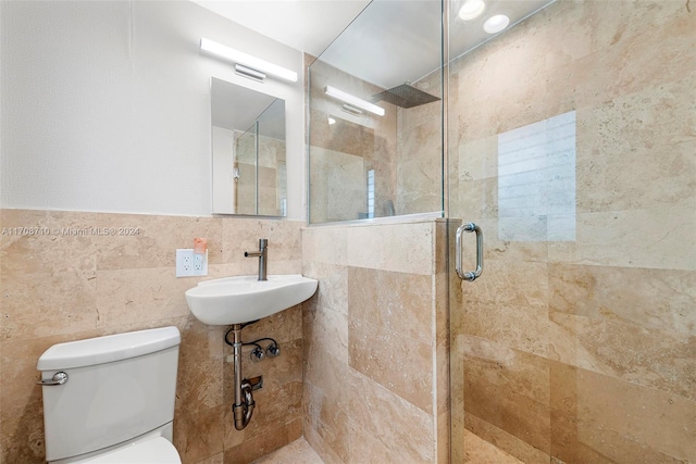 bathroom with toilet, sink, a shower with door, and tile walls