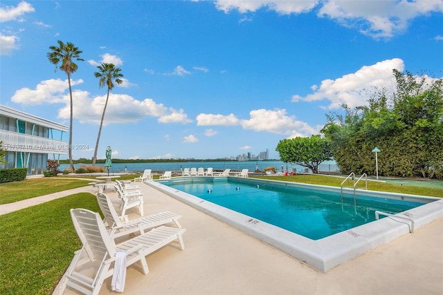 view of swimming pool with a lawn, a water view, and a patio