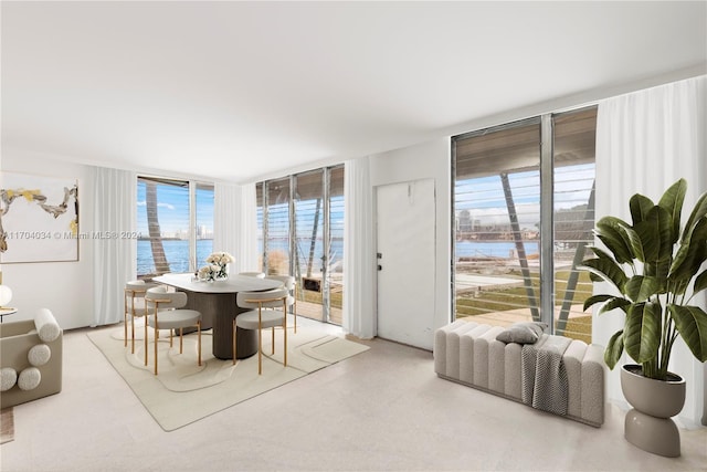 dining area with floor to ceiling windows, a water view, and a healthy amount of sunlight